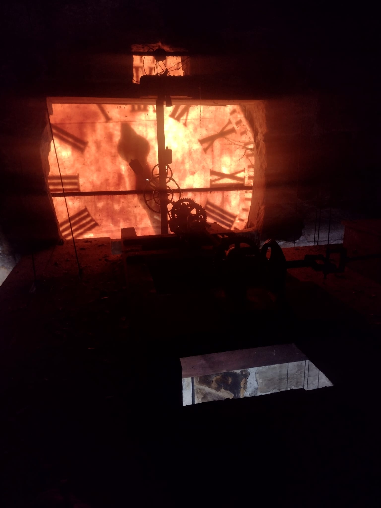The back of a very large clock face viewed from within a dark belfry